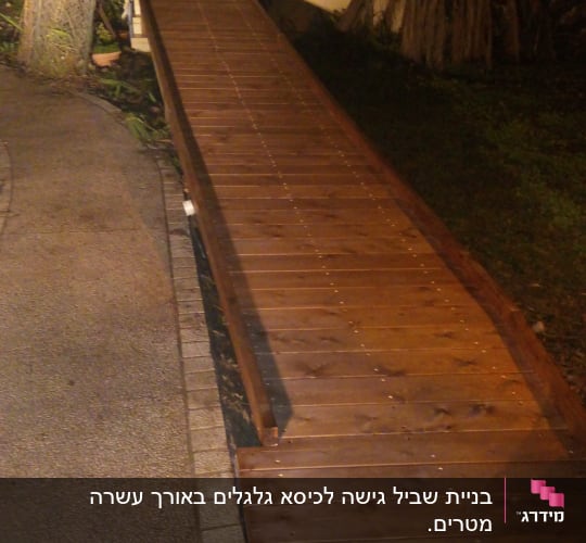 שביל עץ מואר בלילה עם עצים מסביב
